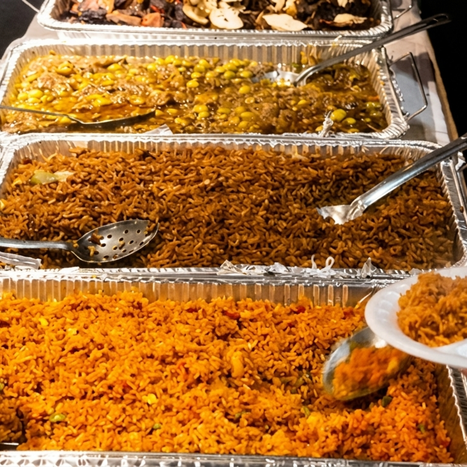 Buffet line with large trays of rice and other dishes, people serving themselves.